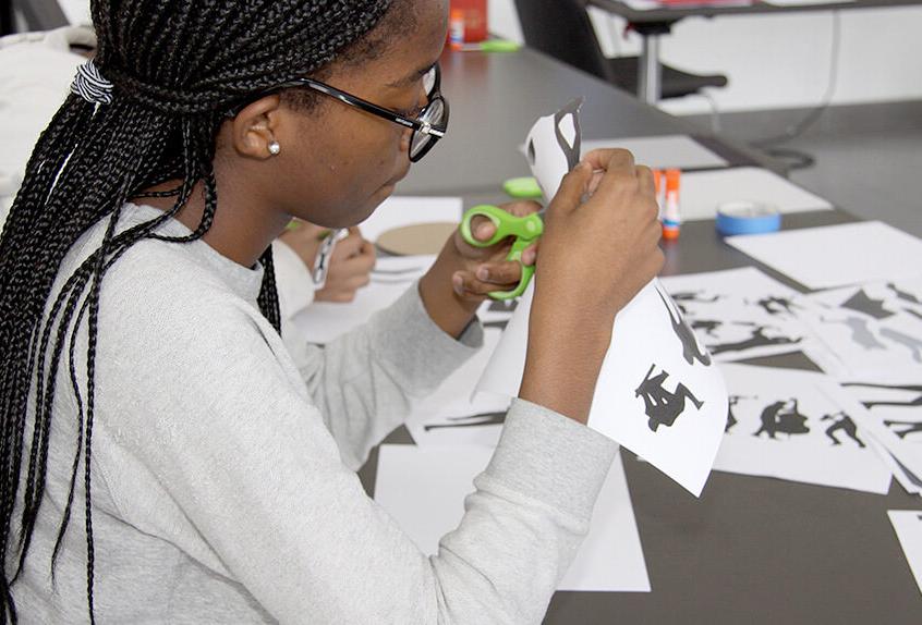 Middle School Harlem Renaissance art project student cutting figures from paper