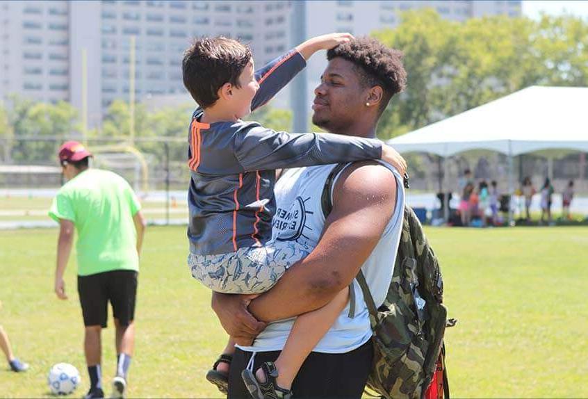 Smiling counselor holding kid at Poly Summer day camp